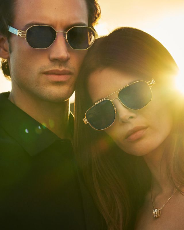 Lunettes de soleil FRED dorées portées par un homme et une femme au coucher du soleil